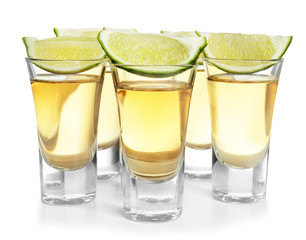 Shots of gold tequila with lime slices isolated on white
