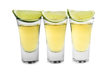 Shots of gold tequila with lime slice in a row isolated on white