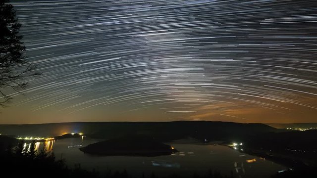 Timelapse sequence of the milky way above lake Rursee in Germany through the short summer night with the stars adding up to star trails.