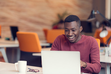 Young business man with a shocked expression working on a laptop