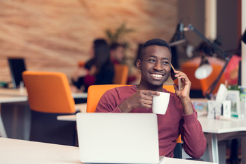 African American businessman on the phone sitting at the computer in his startup office
