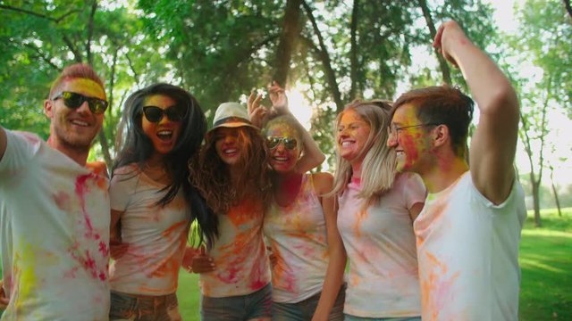 cheerful company of young of different nationality friends having fun in the Park with the colors of Holi