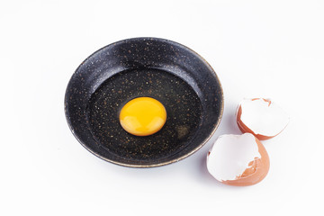 One egg yolks in black bowl and broken egg shells