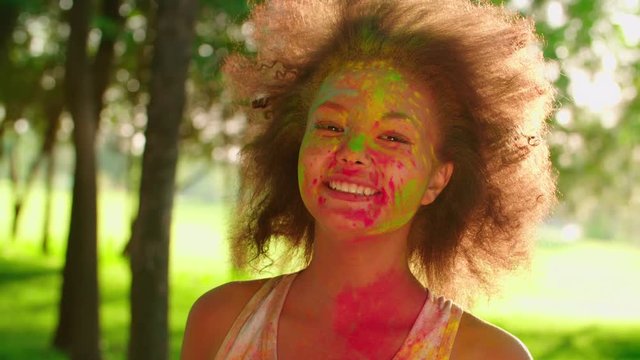closeup of young beautiful African American girl having fun in the Park with the colors of Holi,slow motion