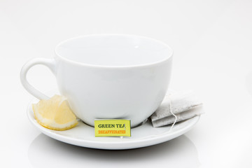 Cup and saucer with lemon wedge and tea bag.
