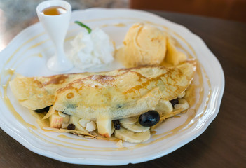 Pancake and fruit with ice cream on table .