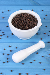 Black pepper in white mortar on blue boards