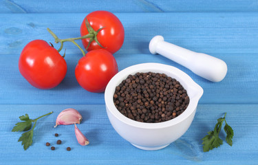 Black pepper in mortar and vegetables on blue boards