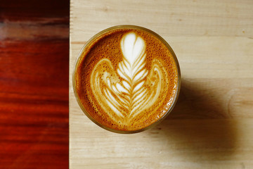 cup of latte art coffee on wooden background