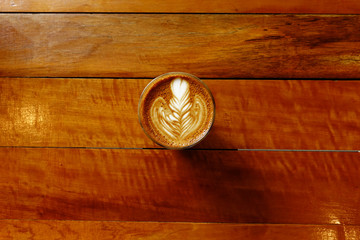 cup of latte art coffee on wooden background