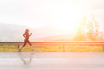 Fototapeta na wymiar Young female runner on rainy road in mountains