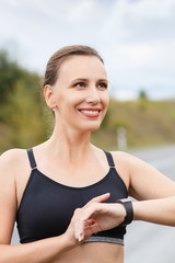 Young smiling fitness woman using her smart watch