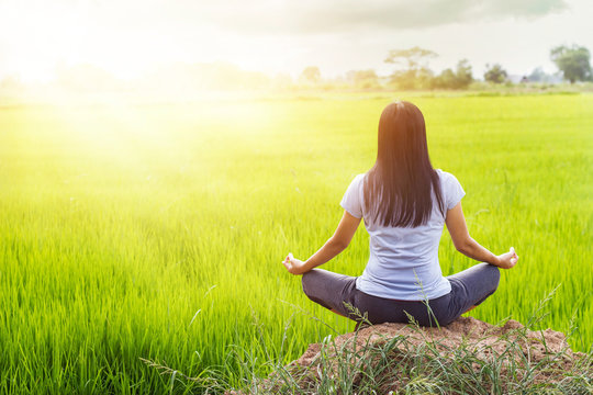 Meditating in the lotus posture on rice field background