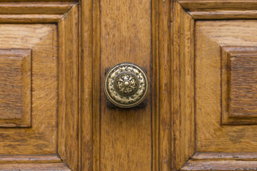 Nahaufnahme eines runden Türknaufs aus Bronze an einer braunen Holztür