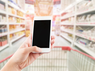 Fototapeta na wymiar Female hand holding mobile smart phone on Supermarket blur backg