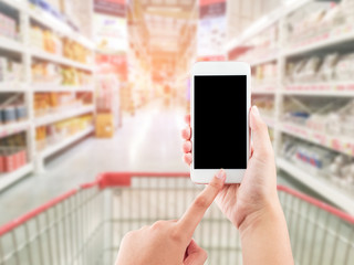 Female hand holding mobile smart phone on Supermarket blur backg