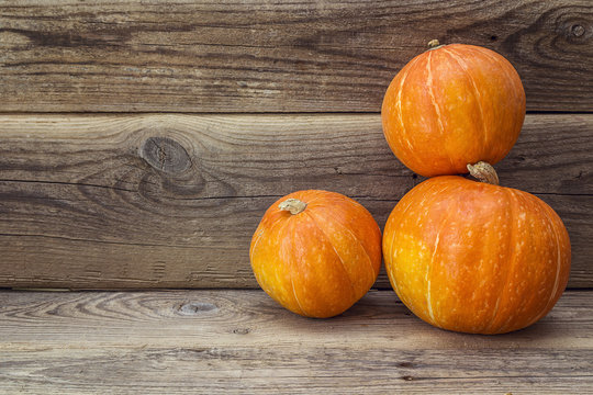 Three orange pumpkin on a background of an old wooden boards.