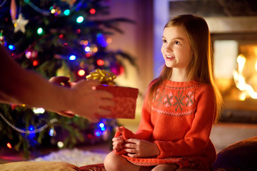 Happy little girl getting a Christmas gift from her parent