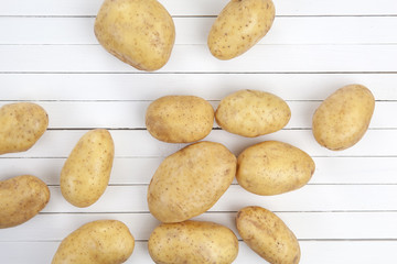 Raw potatoes on a white wooden background, top view