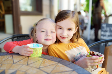 Two little sisters eating ice cream in an outdoor cafe