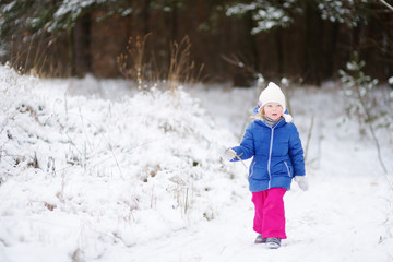 Fototapeta na wymiar Funny little girl having fun in winter park