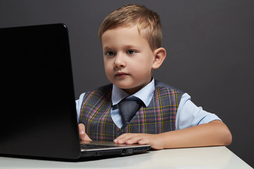 Young boy looking in the notebook screen. funny child with computer