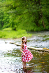 Cute little girl having fun by a river on sunny summer day