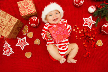 Baby first christmas. Beautiful little baby celebrates Christmas. New Year's holidays. Baby with santa hat with gift. Santa baby.