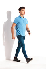 confident young casual man in polo shirt and jeans walking