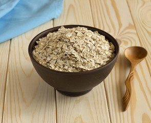 Oat flakes in a bowl on a wooden table.