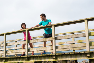 Couple doing stretching exercises workout training outdoor. Young caucasian running couple stretches after jogging outside on beautiful country. Fitness healthy lifestyle.