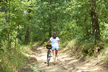 Obraz premium Relaxing outdoor. Young woman riding bike through a field. Rear view.