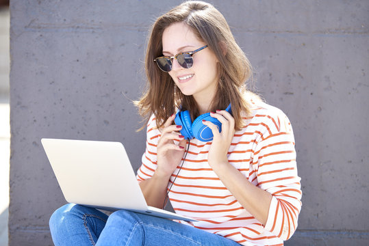Happy young woman working on laptop outdoor.