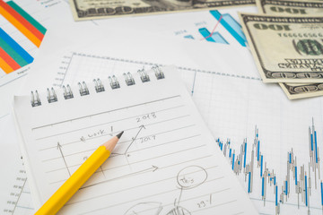 Financial charts on the table with dollars banknotes .