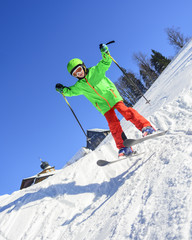 Kind springt mit Skiern über eine kleine Schanze 