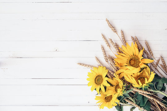 Background with a bouquet of yellow sunflowers and wheat ears on