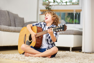 Junge beim Singen und Musizieren auf der Gitarre