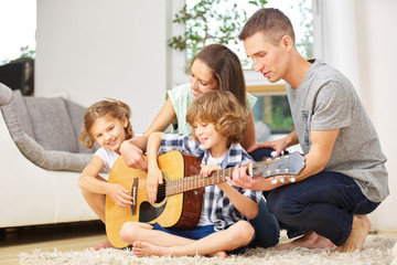 Familie macht zusammen Musik mit Gitarre
