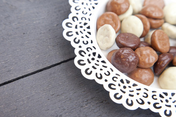 Dutch candy chocolate pepernoten on white plate on black wooden background