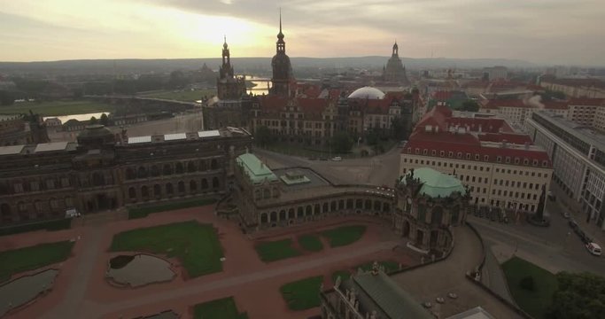 Aerial camera descends over the Zwinger Palace with the Dresden skyline behind. Shot on a cloudy morning at dawn