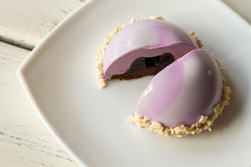 Pink cake on plate. Glazed dessert with filling. Fruit jelly and sweet mousse. Pastry for a party.