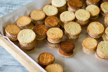 Yellow cookie sandwiches. Wooden tray with sweets. Crispy biscuits with vanilla custard. Cook delicious pastry at home.
