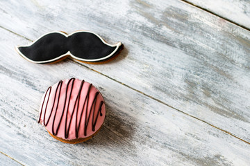Biscuits with glaze. Sweets on wooden background. Moustache cookie and bush cake. Choice of gentleman.