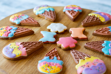 Colorful cookies on wooden board. Biscuits with frosting. Treats from cafe. Crispy glazed sweets.