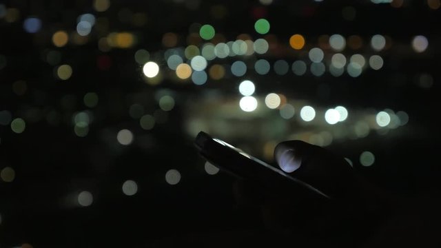 Close up view of woman reading news using smartphone, hands on blurred bokeh lighting background at night