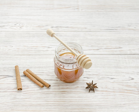 Jar of honey and stick with spices