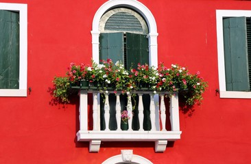 flowered balcony with a window in the house and many flower pots