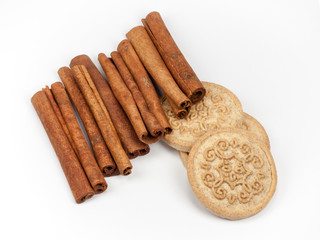 Bunch of cinnamon sticks with cinnamon biscuits isolated on white background