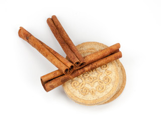 Bunch of cinnamon sticks with cinnamon biscuits isolated on white background