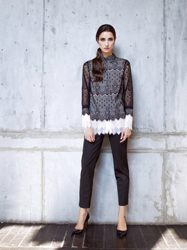 Fashion model wearing black lace shirt and trousers posing in studio